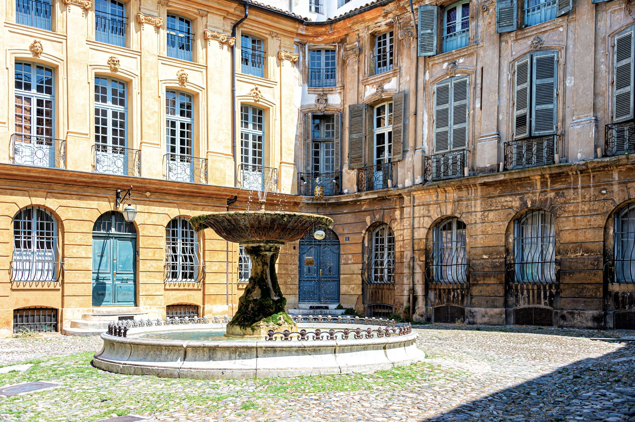 Place pavée et sa fontaine entourée de façades classiques à Aix-en-Provence